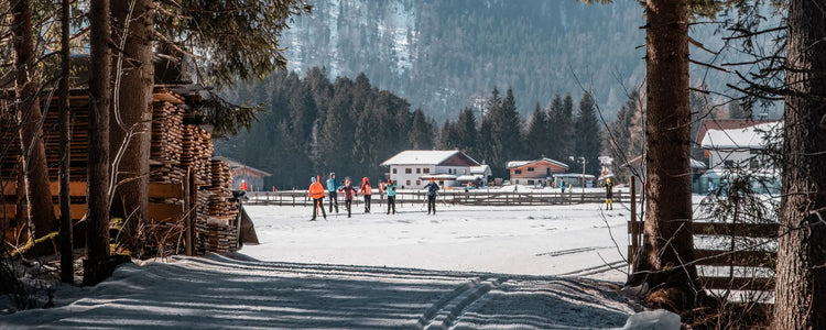 Cross-country skiers on groomed tracks beside an alpine village